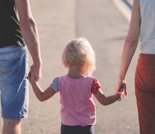 genitori camminano tenendo per mano il figlio