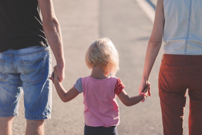 genitori camminano tenendo per mano il figlio