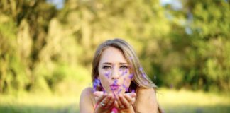 donna in un prato che soffia petali