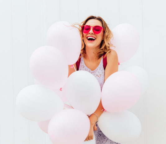 donna felice circondata da palloncini rosa