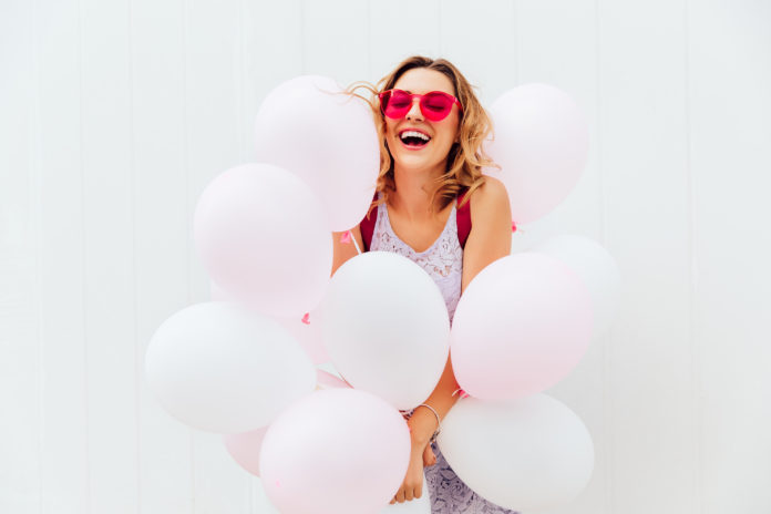 donna felice circondata da palloncini rosa