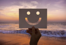mano che mostra uno smile con sfondo tramonto