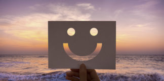 mano che mostra uno smile con sfondo tramonto