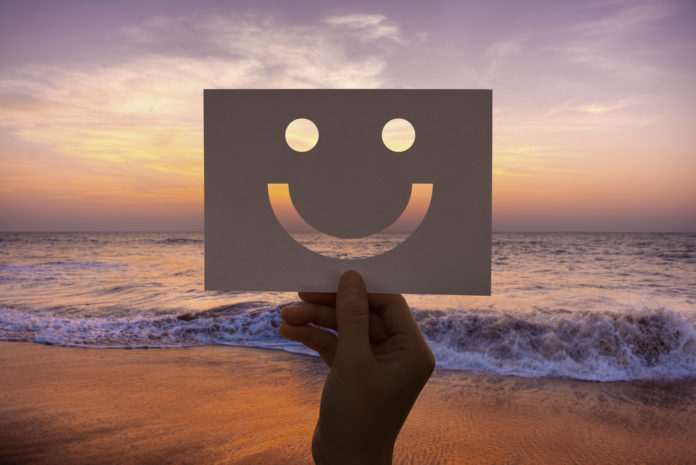 mano che mostra uno smile con sfondo tramonto