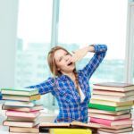 donna che sbadiglia davanti ai libri