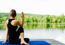 donna in posizione yoga in riva al lago