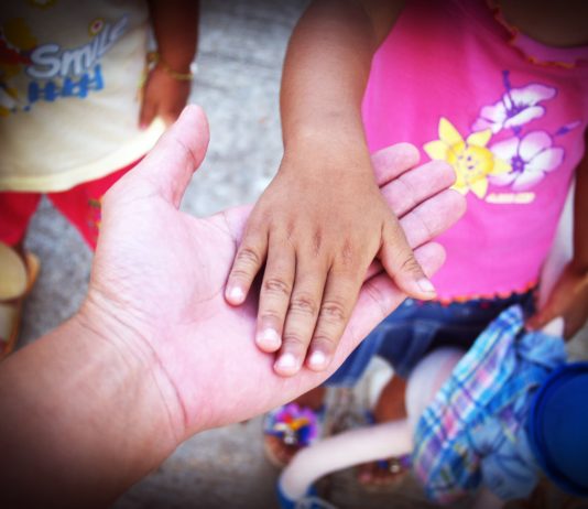 mano adulta sotto la mano di una bambina