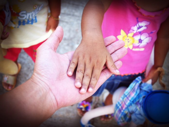 mano adulta sotto la mano di una bambina