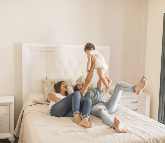 mamma, papà e figlio sul letto che giocano