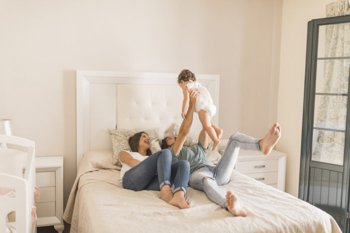 mamma, papà e figlio sul letto che giocano