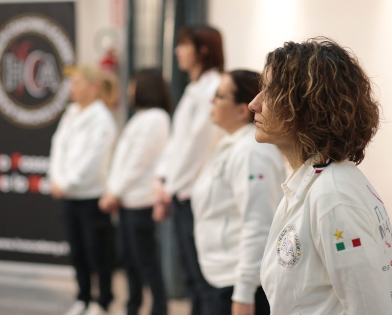 Gruppo di professionisti Health Coaching Academy in divisa bianca allineati durante un momento formativo.