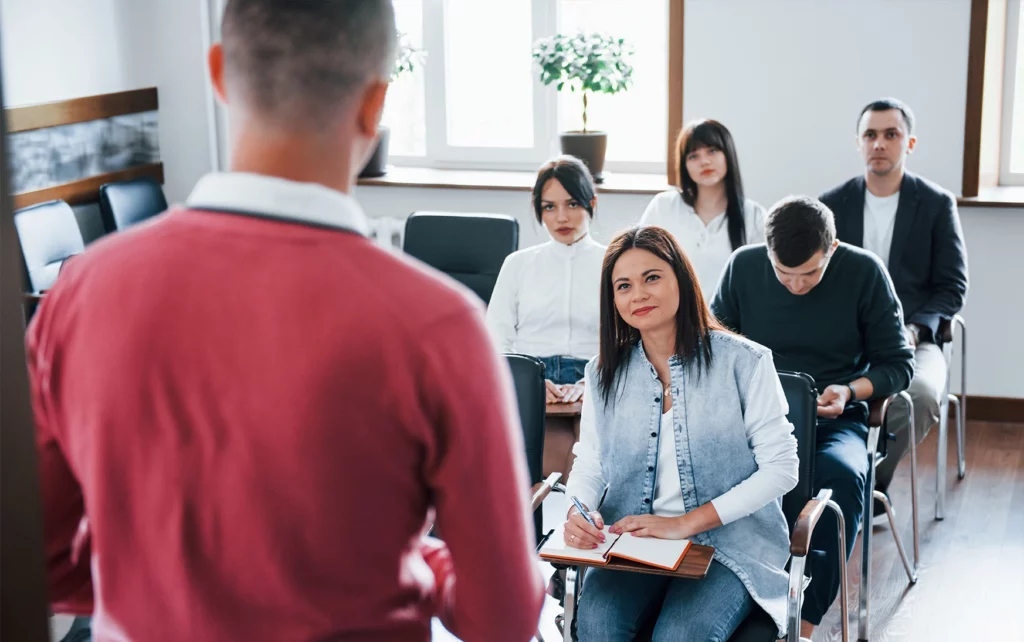 Docente che parla a un gruppo di partecipanti in aula durante la formazione universitaria