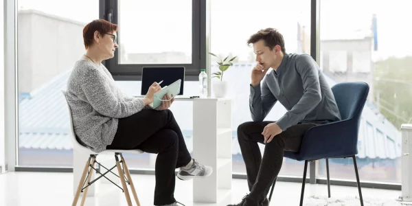 Coach che dialoga con un coachee durante una sessione individuale di Life Coaching in un ambiente luminoso.