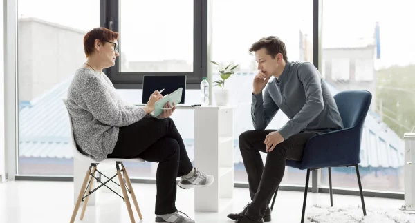 Coach che dialoga con un coachee durante una sessione individuale di Life Coaching in un ambiente luminoso.