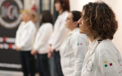 Gruppo di professionisti Health Coaching Academy in divisa bianca allineati durante un momento formativo.