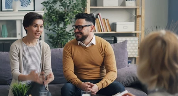 Coach che dialoga con una coppia di genitori durante una sessione di supporto familiare.